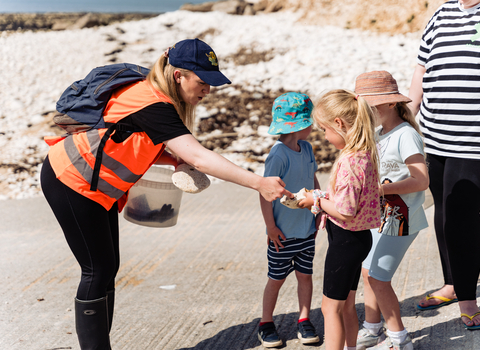 Session leader in hi-vis jacket pointing out a species to a child